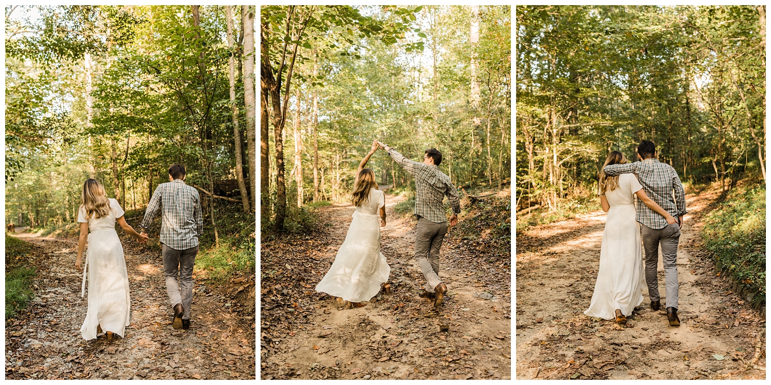 Newly engaged couple in Lullwater Park walking and dancing and holding hands on a trail during an engagement session in a lush, green forest in Atlanta, GA