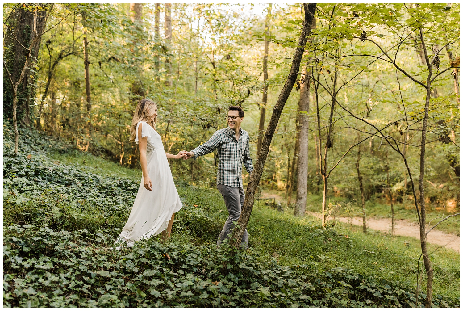 Newly engaged couple in Lullwater Park walking on a trail during an engagement session in a lush, green forest in Atlanta, GA