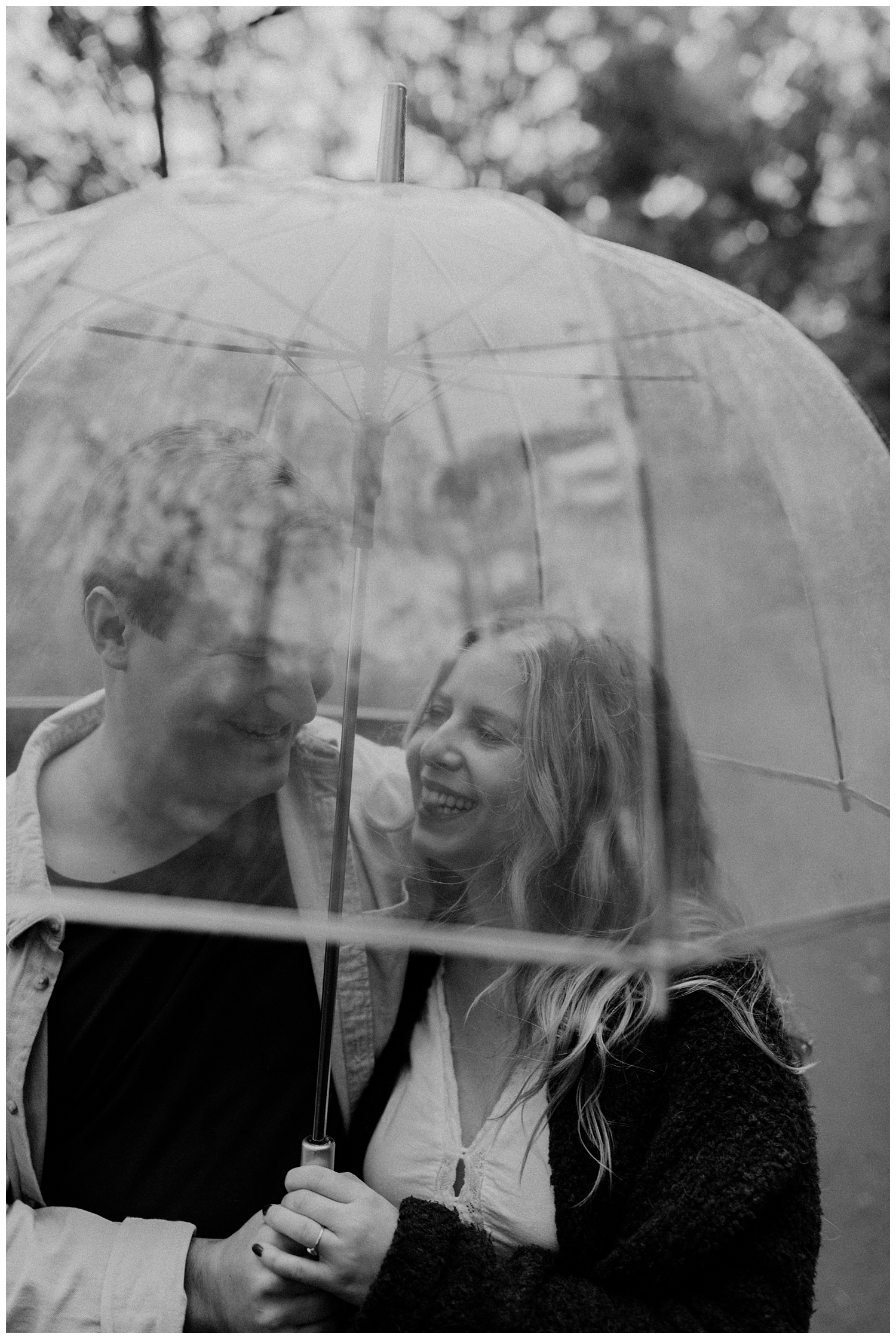 Rainy Day Engagement Session in Marietta, Georgia with cute couple laughing in the rain under a clear umbrella