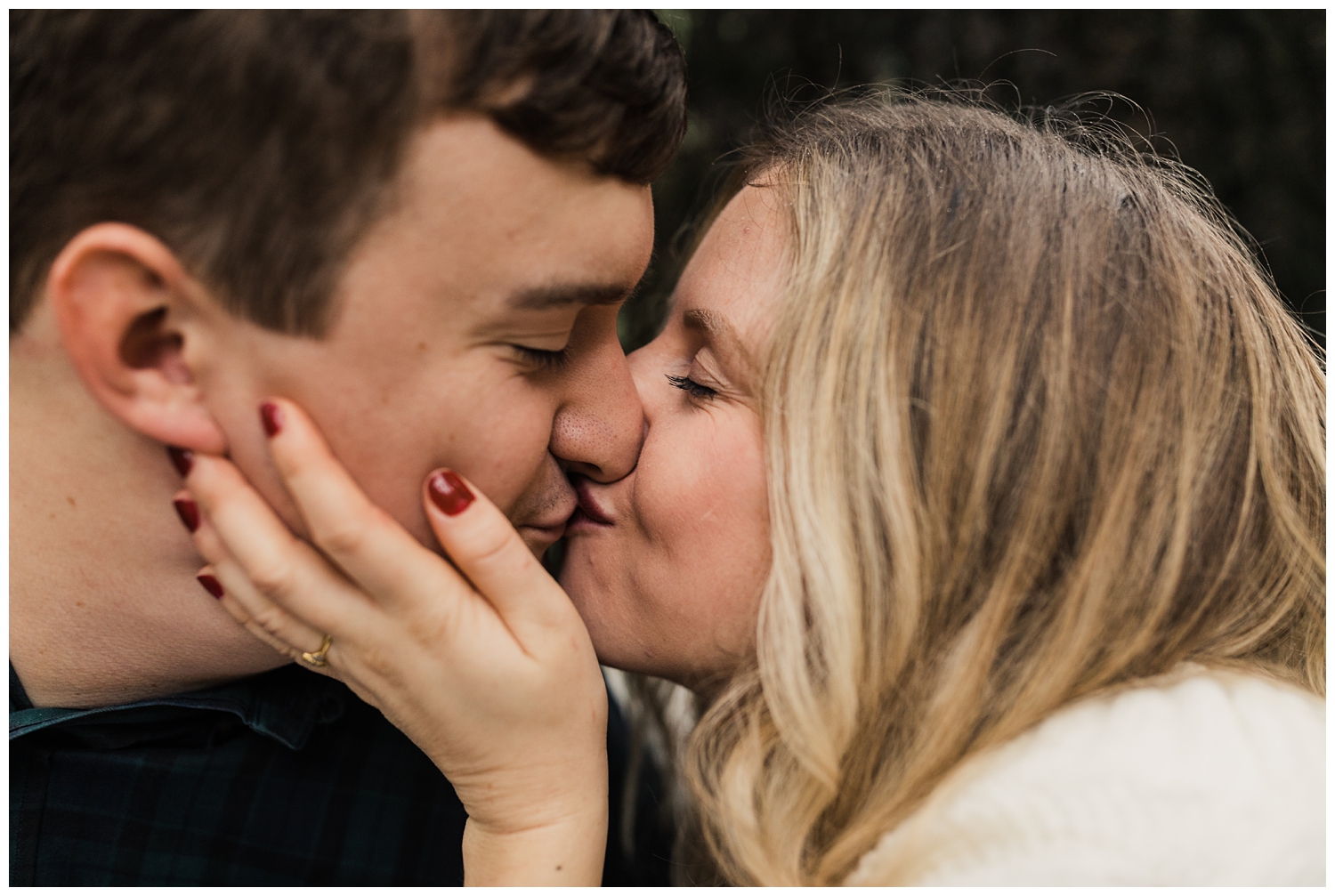 rainy day engagement session in marietta, georgia with cute couple sitting and kissing under a tree